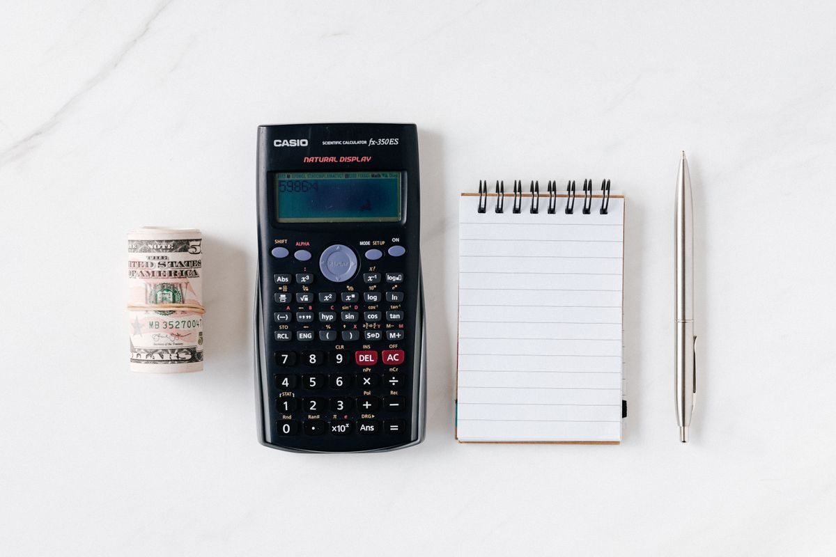 Calculator with money and notebook representing Google Ads cost and budget planning